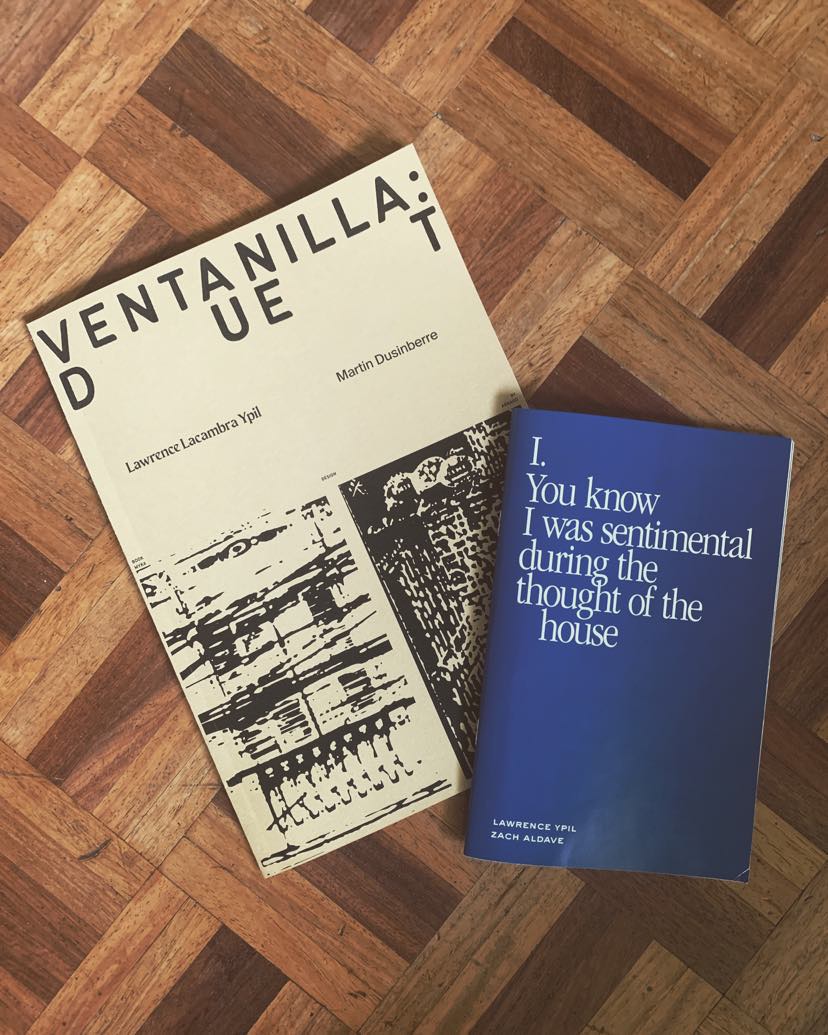 Two books on a wooden platform. First book is entitled Ventanilla Duet, by Lawrence Lacambra Ypil and Martin Dusinberre. Cover is white with abstract black ink-like design. Second book is entitled You know I was sentimental during the thought of the house, by Lawrence Ypil and Zach Aldave. Cover is plain blue.